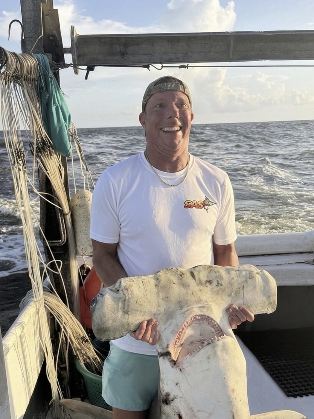Angler holding up a hammerhead shark head catch aboard the boat