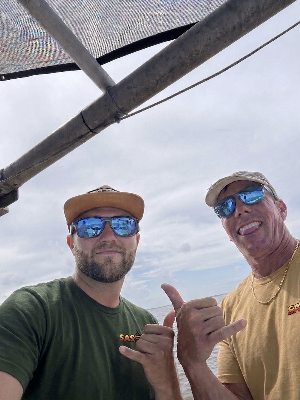 Two anglers in SAS shirts giving the hang loose sign aboard the boat